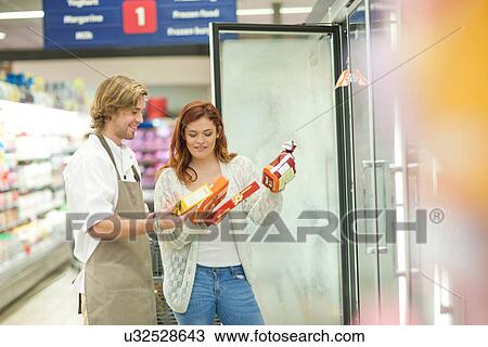 Stock Image - Young male sales assistant advising customer. Fotosearch