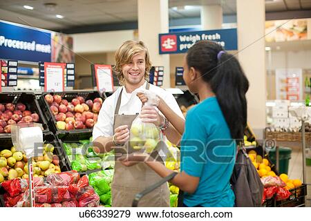 Young male sales assistant handing apples to customer View Large Photo Image Stock Photo - Young male sales assistant handing apples to customer. Fotosearch