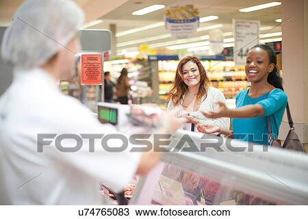 Young male sales assistant serving customers at counter View Large Photo Image Stock Image - Young male sales assistant serving customers at counter. Fotosearch