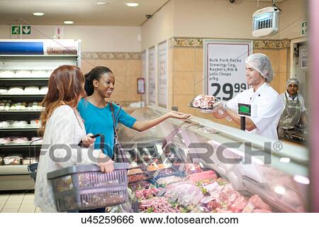 Young male sales assistant serving female customers View Large Photo Image Stock Photograph - Young male sales assistant serving female customers. Fotosearch
