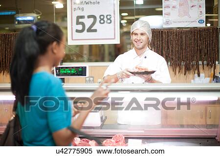 Young male sales assistant serving customer View Large Photo Image Stock Photography - Young male sales assistant serving customer. Fotosearch