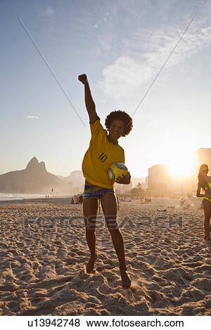 Young man cheering with football, Ipanema Beach, Rio, Brazil View Large Photo Image Stock Photo - Young man cheering with football, Ipanema Beach, Rio, Brazil. Fotosearch