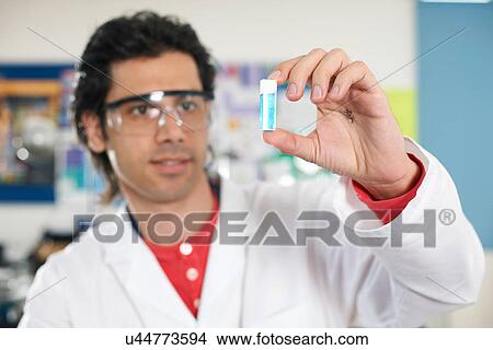 Young man holding chemical sample View Large Photo Image Picture - Young man holding chemical sample. Fotosearch