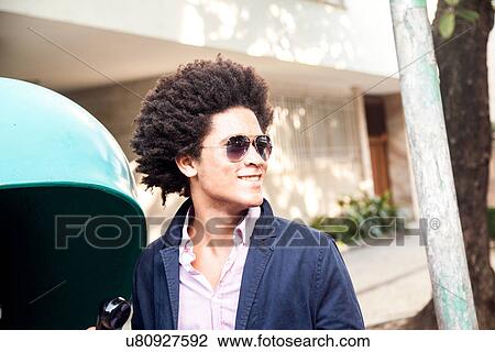 Stock Image - Young man in sunglasses by pay telephone. Fotosearch