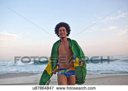 Young man on beach, wrapped in Brazilian Flag View Large Photo Image Stock Photo - Young man on beach, wrapped in Brazilian Flag. Fotosearch
