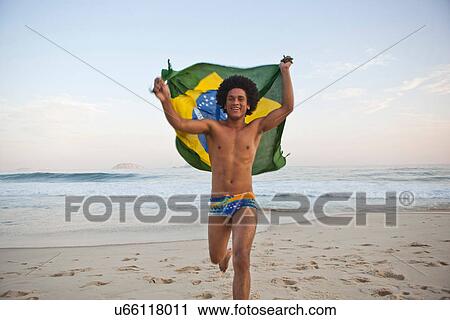 Young man running on beach with Brazilian Flag View Large Photo Image Stock Image - Young man running on beach with Brazilian Flag. Fotosearch