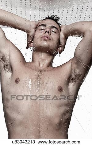 Stock Image - Young man showering, studio shot. Fotosearch