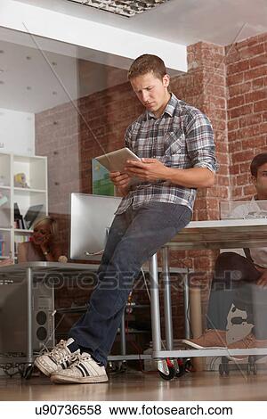 Young man using digital tablet in modern office View Large Photo Image Stock Photo - Young man using digital tablet in modern office. Fotosearch