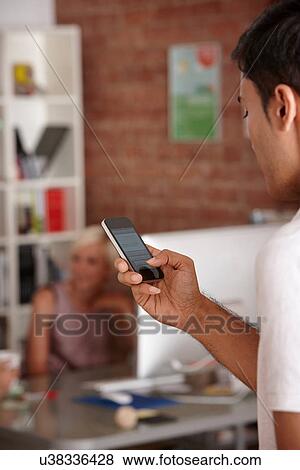 Stock Photo - Young man using smartphone. Fotosearch
