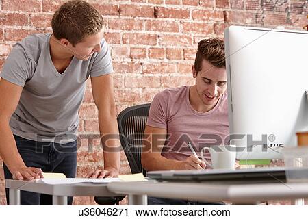 Young men talking at desk with computer View Large Photo Image Stock Image - Young men talking at desk with computer. Fotosearch