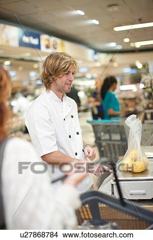 Picture - Young sales assistant weighing apples. Fotosearch