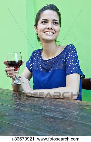 Stock Image - Young woman at table outside cafe with wine. Fotosearch