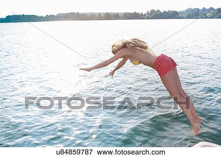 Stock Photo - Young woman diving into lake. Fotosearch
