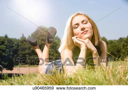 Young woman enjoying sunshine in park View Large Photo Image Stock Photo - Young woman enjoying sunshine in park. Fotosearch