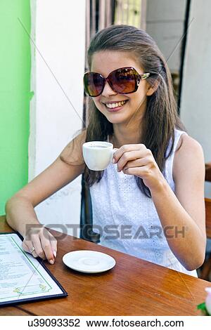 Stock Image - Young woman having espresso outside cafe. Fotosearch