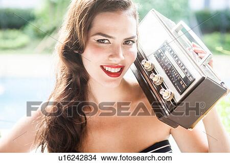 Picture - Young woman holding vintage radio. Fotosearch