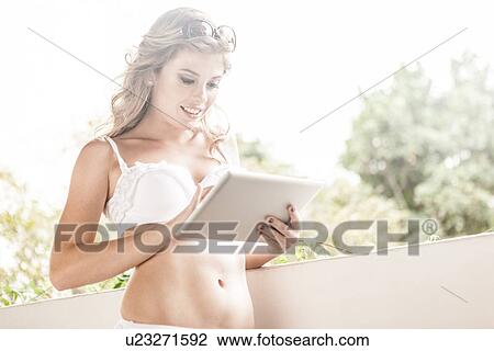 Young woman in bikini top, using digital tablet View Large Photo Image Stock Image - Young woman in bikini top, using digital tablet. Fotosearch