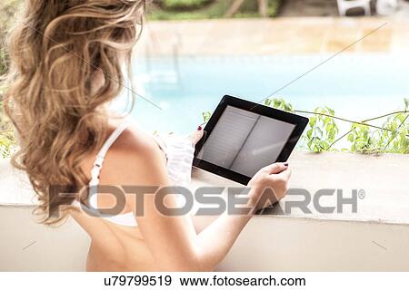 Young woman in bikini top, using digital tablet View Large Photo Image Stock Photo - Young woman in bikini top, using digital tablet. Fotosearch