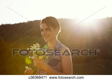 Young woman in meadow with bunch of wild flowers View Large Photo Image Stock Image - Young woman in meadow with bunch of wild flowers. Fotosearch