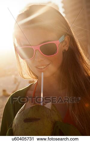 Young woman in sunlight with coconut drink View Large Photo Image Stock Image - Young woman in sunlight with coconut drink. Fotosearch