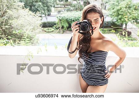 Picture - Young woman looking through camera viewfinder. Fotosearch