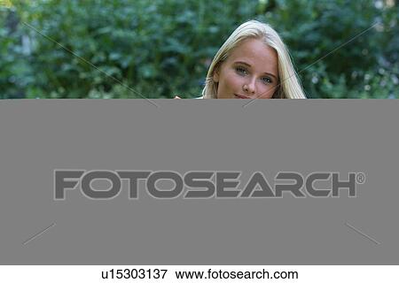 Young woman looking up from book View Large Photo Image Stock Photo - Young woman looking up from book. Fotosearch