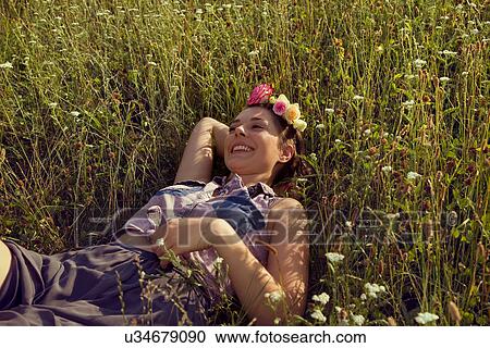 Stock Image - Young woman lying in meadow with flowers in her hair. Fotosearch