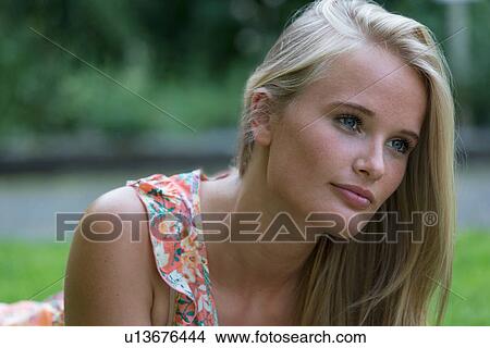 Young woman lying on stomach looking into distance View Large Photo Image Picture - Young woman lying on stomach looking into distance. Fotosearch