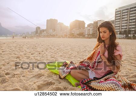 Stock Image - Young woman meditating, Ipanema Beach, Rio de Janeiro, Brazil. Fotosearch