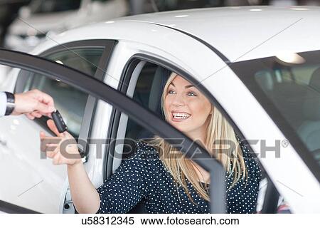 Young woman sitting in new car with key in showroom View Large Photo Image Stock Photography - Young woman sitting in new car with key in showroom. Fotosearch