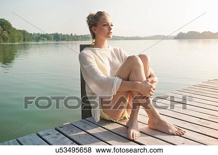 Young woman sitting on lake pier View Large Photo Image Stock Photo - Young woman sitting on lake pier. Fotosearch