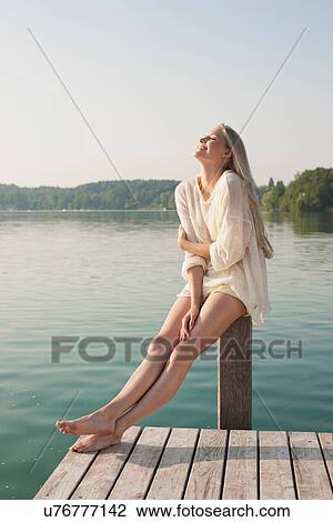 Young woman sitting on pier post View Large Photo Image Stock Image - Young woman sitting on pier post. Fotosearch