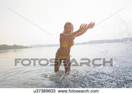 Young woman splashing water in lake View Large Photo Image Stock Image - Young woman splashing water in lake. Fotosearch