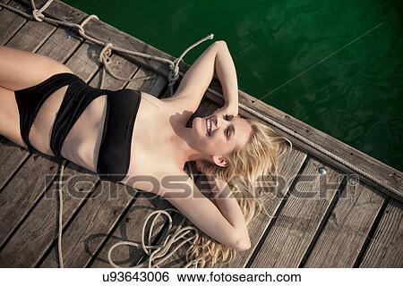 Young woman sunbathing on pier View Large Photo Image Stock Photograph - Young woman sunbathing on pier. Fotosearch