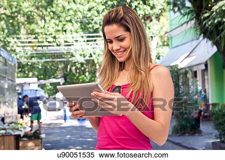 Stock Photography - Young woman using digital tablet in street. Fotosearch