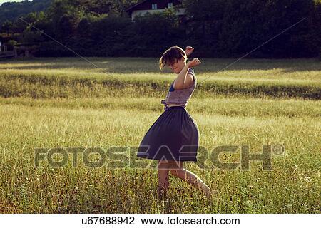 Stock Image - Young woman walking through meadow. Fotosearch