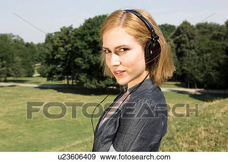 Young woman wearing headphones in park View Large Photo Image Stock Photo - Young woman wearing headphones in park. Fotosearch