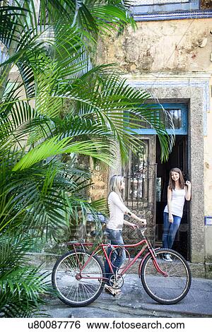 Young woman with bicycle talking to friend in doorway, Rio de Janeiro, Brazil View Large Photo Image Stock Photograph - Young woman with bicycle talking to friend in doorway, Rio de Janeiro, Brazil. Fotosearch