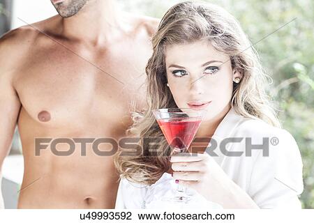 Young woman with cocktail, bare chested man in background View Large Photo Image Stock Image - Young woman with cocktail, bare chested man in background. Fotosearch