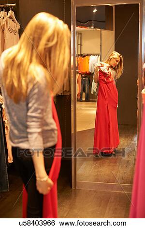 Stock Photograph - Young woman with red dress in fitting room. Fotosearch