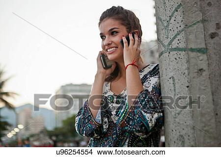 Picture - Young woman with two cellphones. Fotosearch