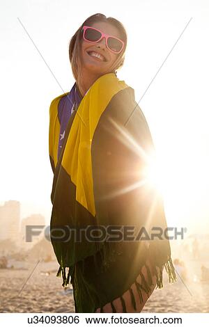 Stock Photograph - Young woman wrapped in Brazilian Flag in sunlight. Fotosearch