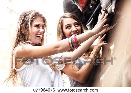 Stock Photograph - Young women looking at handbags in market. Fotosearch