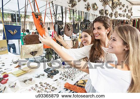 Young women looking at souvenirs in market View Large Photo Image Stock Photo - Young women looking at souvenirs in market. Fotosearch