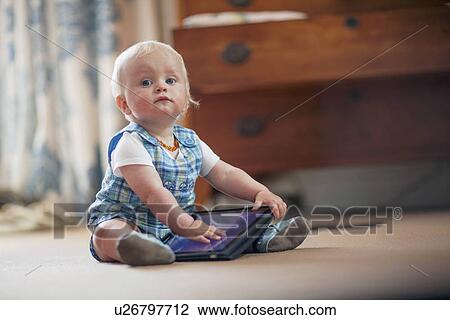 Baby boy (12-17 months) playing with digital tablet View Large Photo Image Stock Image - Baby boy (12-17 months) playing with digital tablet. Fotosearch