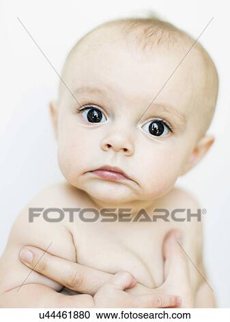Stock Image - Baby boy (6-11 months) held by adult. Fotosearch