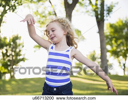 Stock Image - Blonde girl (4-5) dancing in park. Fotosearch