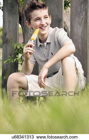 Boy (12-13) sitting in grass and eating ice cream View Large Photo Image Stock Image - Boy (12-13) sitting in grass and eating ice cream. Fotosearch