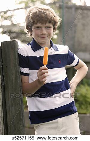 Boy (12-13) standing and eating ice cream View Large Photo Image Stock Photography - Boy (12-13) standing and eating ice cream. Fotosearch