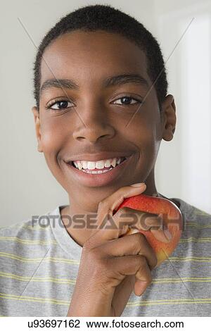 Stock Image - Boy (14-15) holding apple. Fotosearch